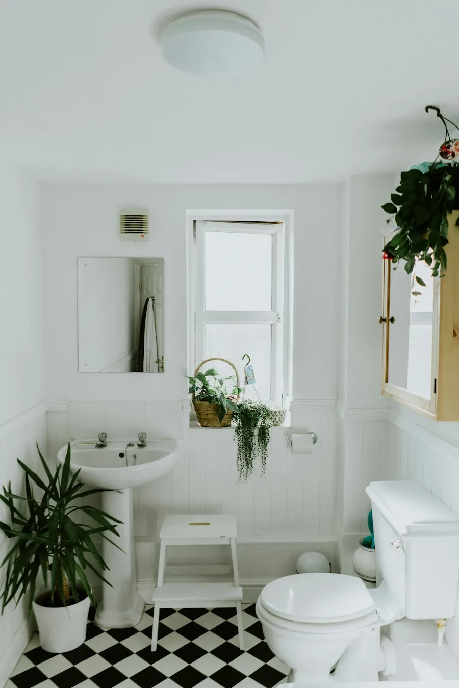 Bright white bathroom with a refinished pedestal sink and checkered tile floor in Irvine