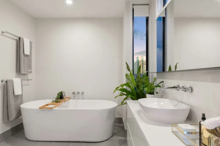 Freestanding white bathtub and vessel sink after reglazing in an Irvine bathroom