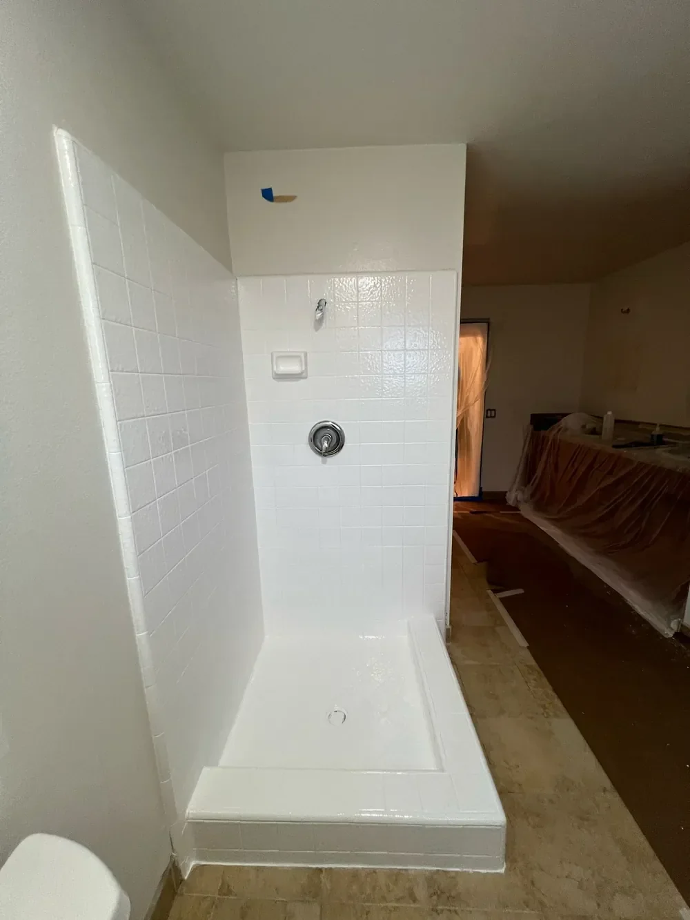 Tile shower stall after reglazing: walls, curb and floor in one glossy white finish
