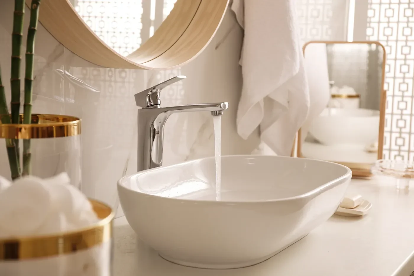 Glossy white vessel sink with a chrome faucet running on a refinished vanity in an Irvine bathroom