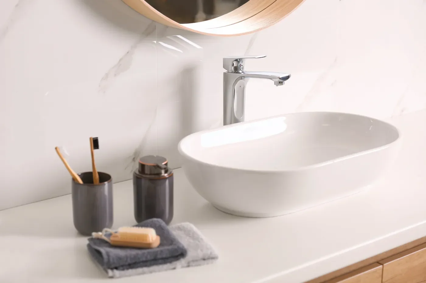 Refinished white vessel sink on a bright vanity with marble-look walls in an Irvine bathroom